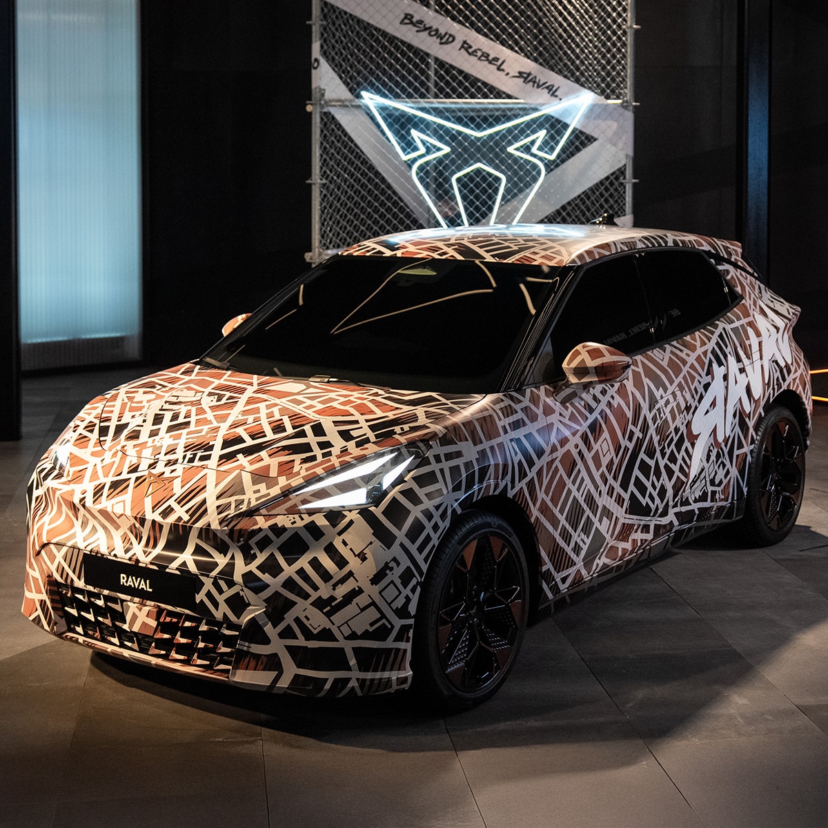 CUPRA raval gecamoufleerd elektrische auto met verlicht CUPRA logo op de achtergrond