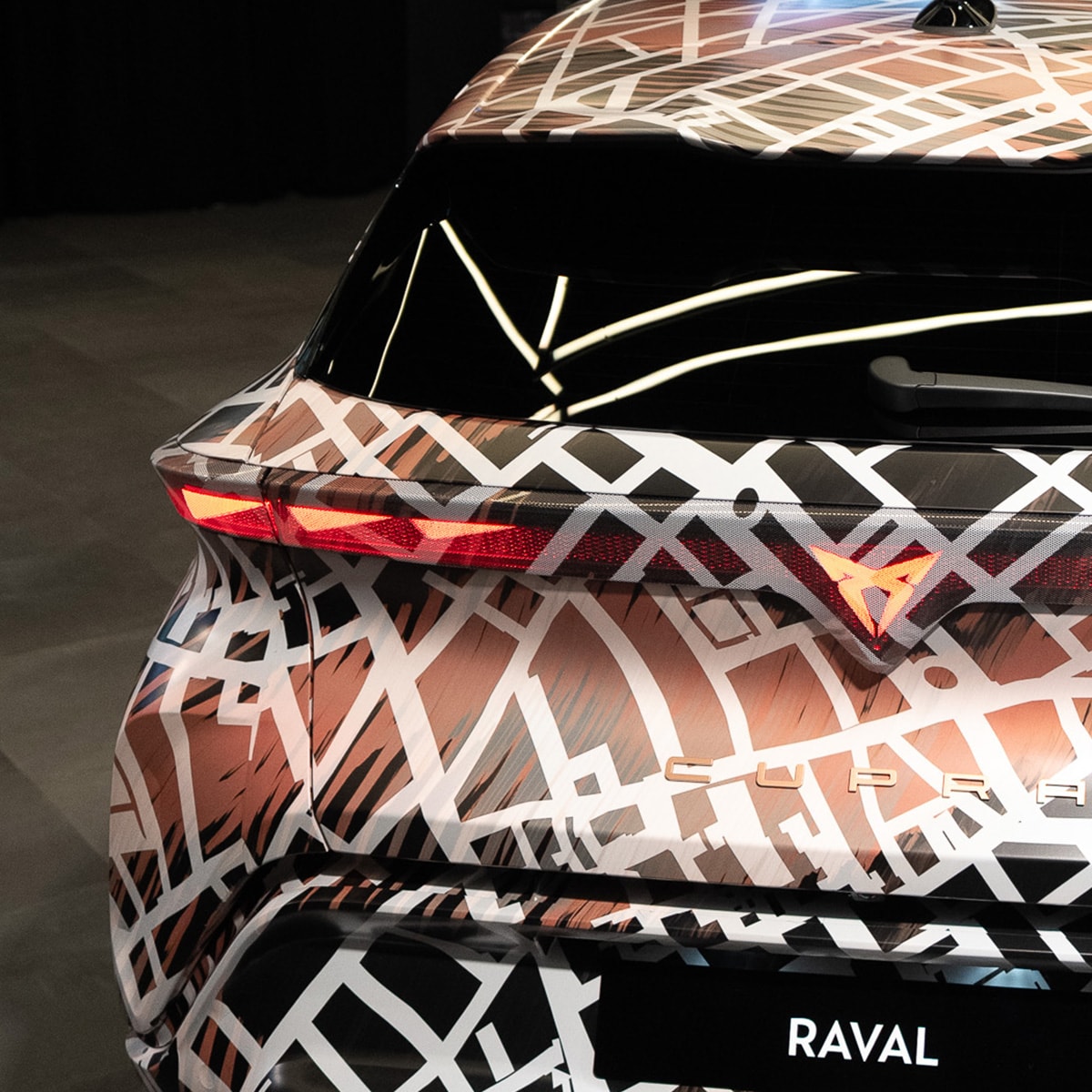 CUPRA raval gecamoufleerd elektrische auto close up van de achterlichten en verlicht CUPRA logo achterop