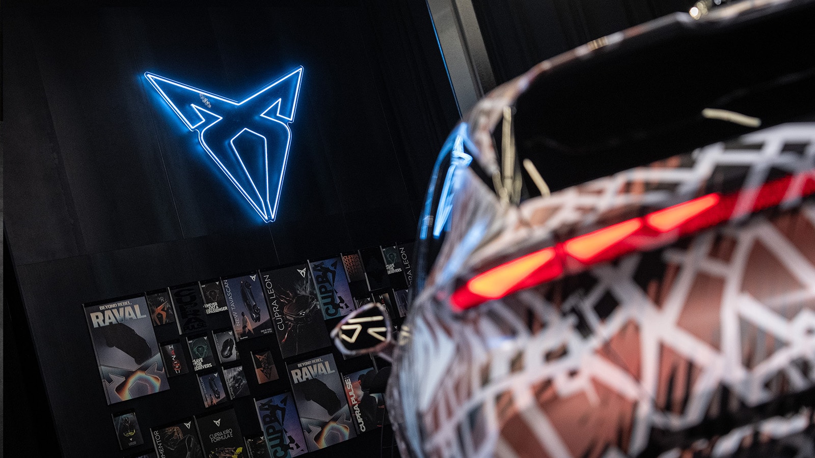 CUPRA raval gecamoufleerd sportieve elektrische auto met verlicht CUPRA logo op de achtergrond