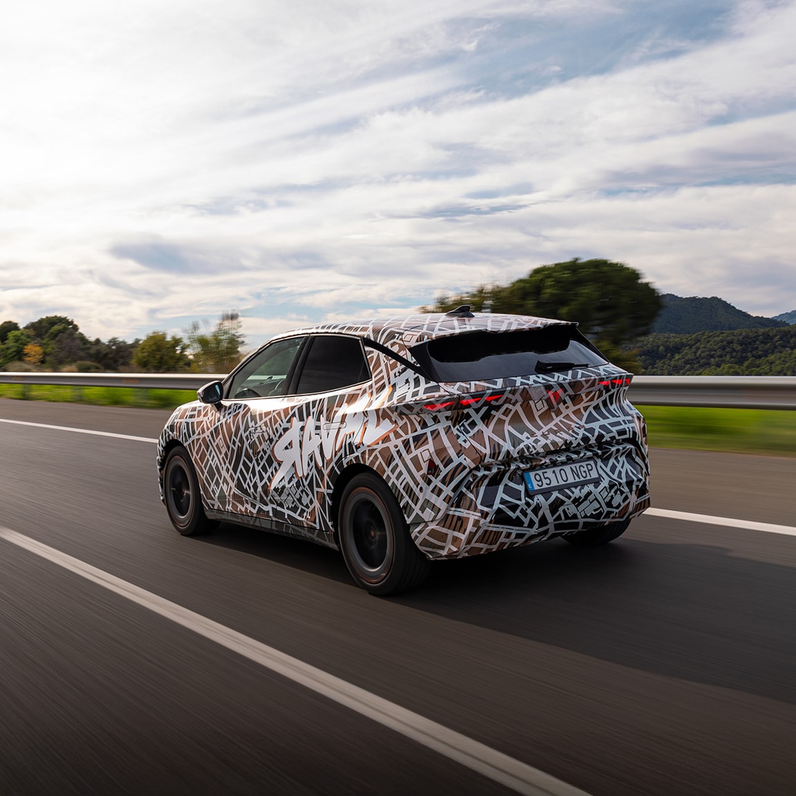 Een close-up van een slanke, zwarte elektrische auto wandlader gemonteerd op een grijze muur. De lader heeft het witte CUPRA logo en een groene indicatorlamp die de laadstatus aangeeft.